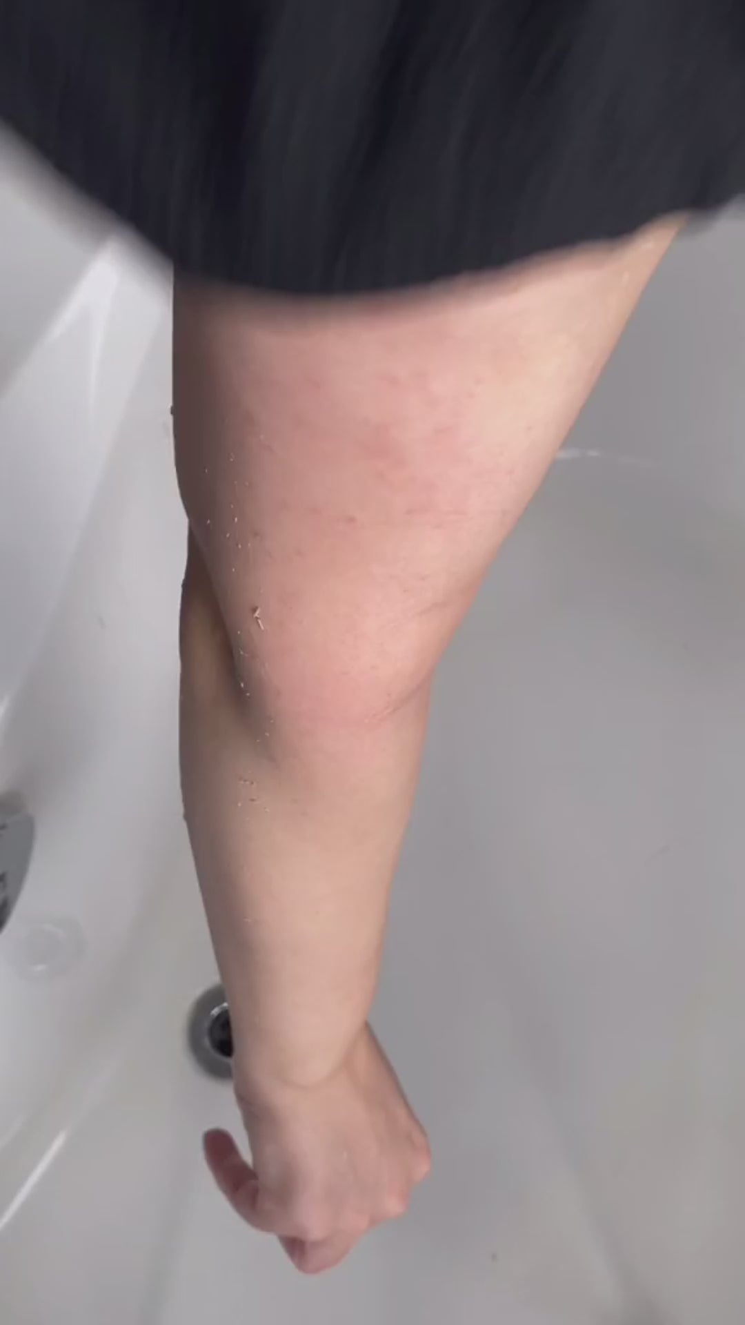 Woman demonstrating exfoliating mitt kessa scrub glove on leg for self-tanning preparation and shower