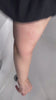 Woman demonstrating exfoliating mitt kessa scrub glove on leg for self-tanning preparation and shower